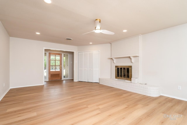 unfurnished living room with a brick fireplace, light hardwood / wood-style floors, and ceiling fan