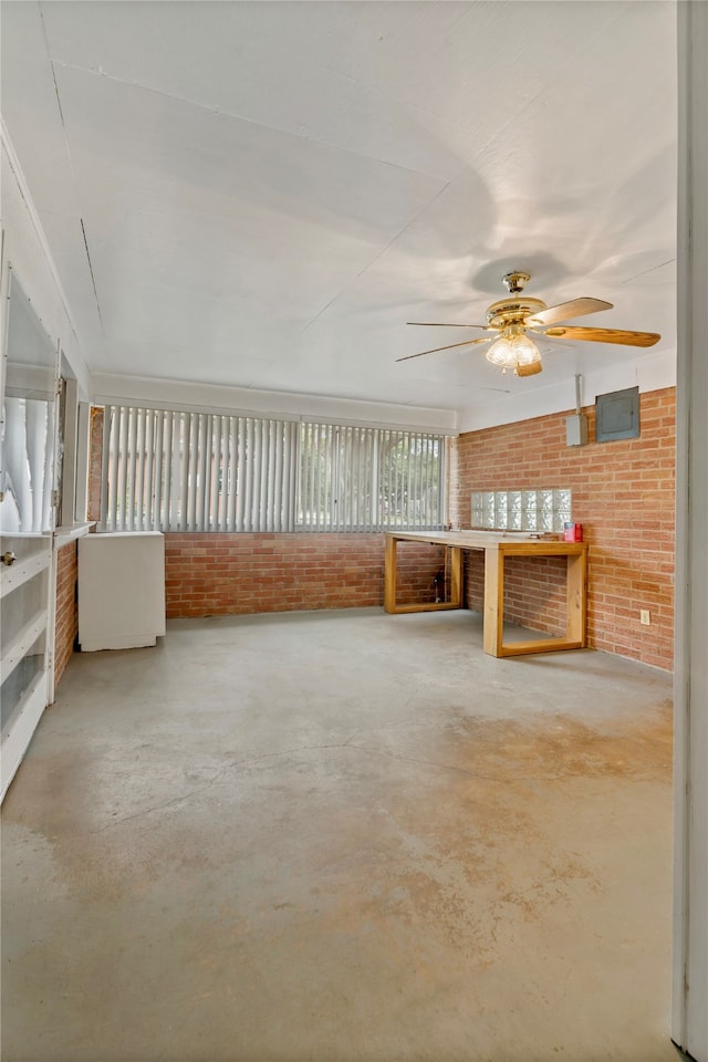 interior space featuring concrete flooring, ceiling fan, and brick wall