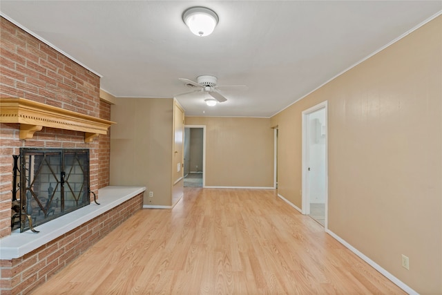 unfurnished living room featuring light hardwood / wood-style floors, crown molding, a fireplace, and ceiling fan