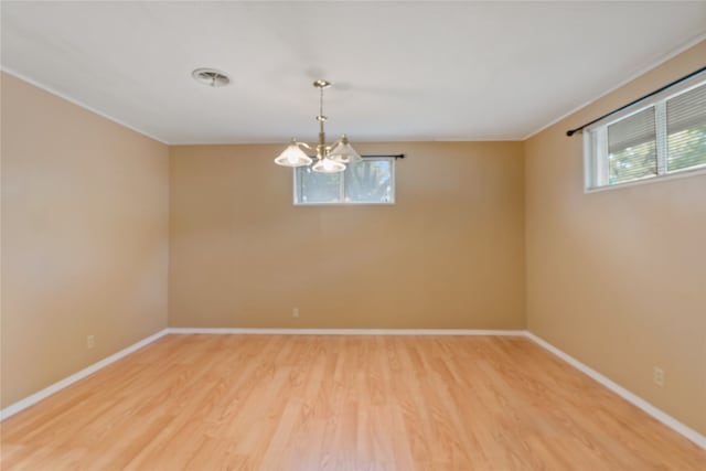 empty room with a notable chandelier, crown molding, hardwood / wood-style floors, and plenty of natural light