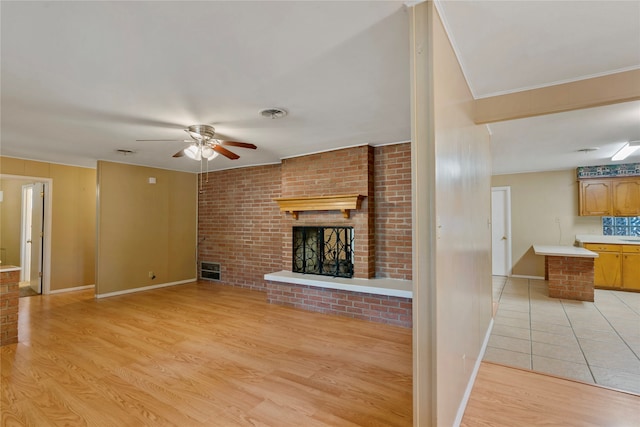 living room featuring a brick fireplace, light wood-type flooring, and ceiling fan