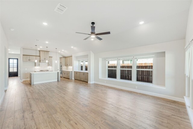 unfurnished living room with lofted ceiling, ceiling fan, and light wood-type flooring