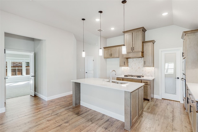 kitchen with decorative light fixtures, an island with sink, tasteful backsplash, and sink