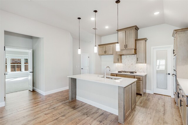 kitchen with hanging light fixtures, oven, a kitchen island with sink, and built in microwave