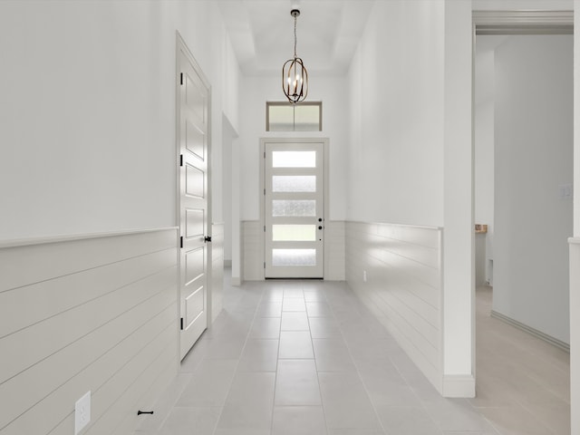 tiled entryway featuring an inviting chandelier