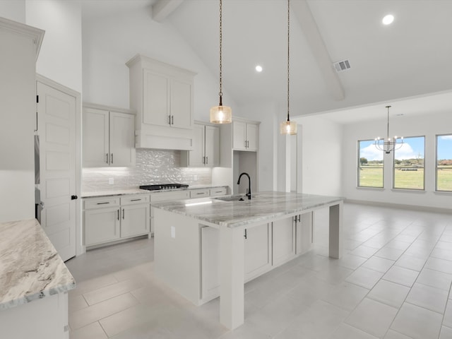 kitchen featuring a kitchen island with sink, beamed ceiling, hanging light fixtures, and a notable chandelier