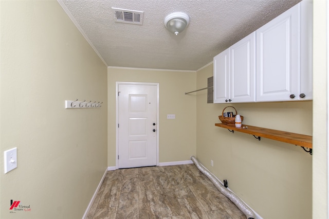 clothes washing area featuring cabinets, ornamental molding, a textured ceiling, and light hardwood / wood-style floors