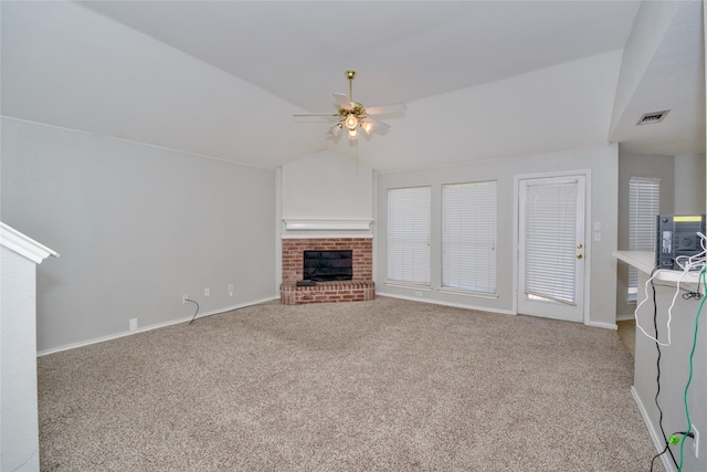 unfurnished living room featuring ceiling fan, carpet floors, a brick fireplace, and vaulted ceiling