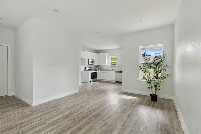 unfurnished living room featuring light wood-type flooring and sink