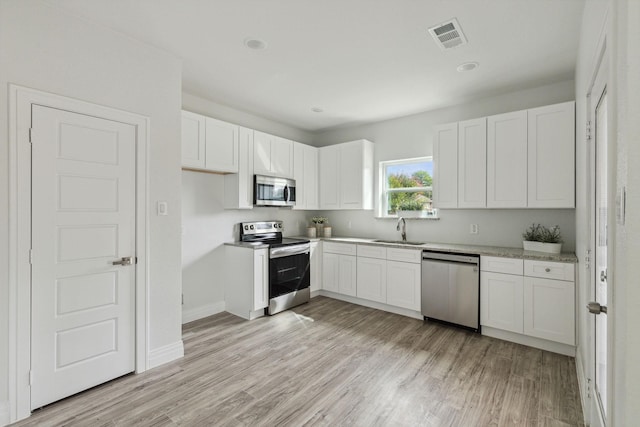 kitchen with light hardwood / wood-style flooring, white cabinets, sink, and stainless steel appliances