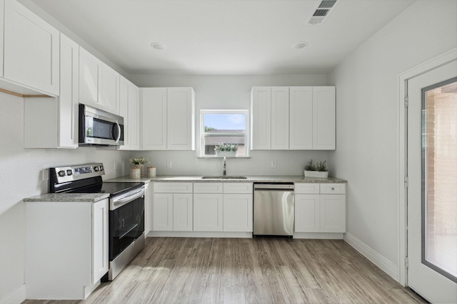 kitchen with light wood-type flooring, appliances with stainless steel finishes, sink, and white cabinets