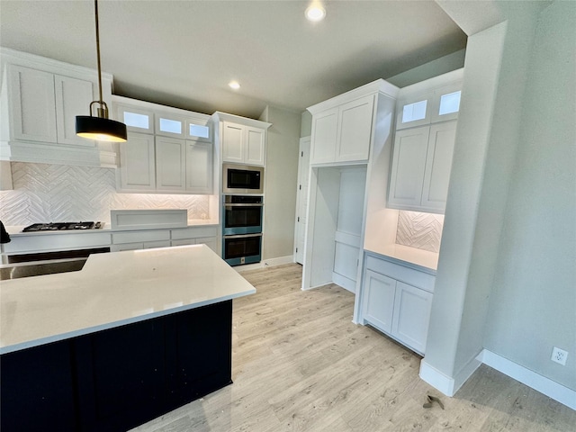 kitchen with backsplash, white cabinets, pendant lighting, and stainless steel appliances