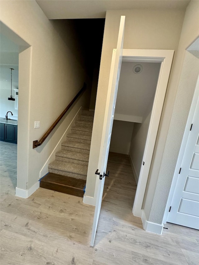 staircase featuring wood-type flooring and sink