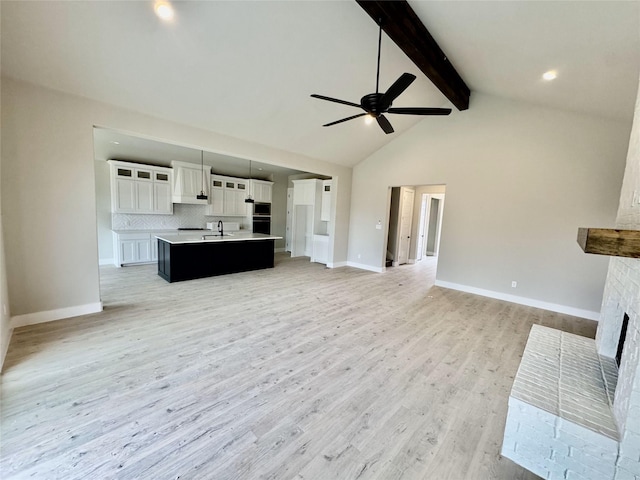 unfurnished living room featuring high vaulted ceiling, a brick fireplace, light hardwood / wood-style flooring, ceiling fan, and beamed ceiling