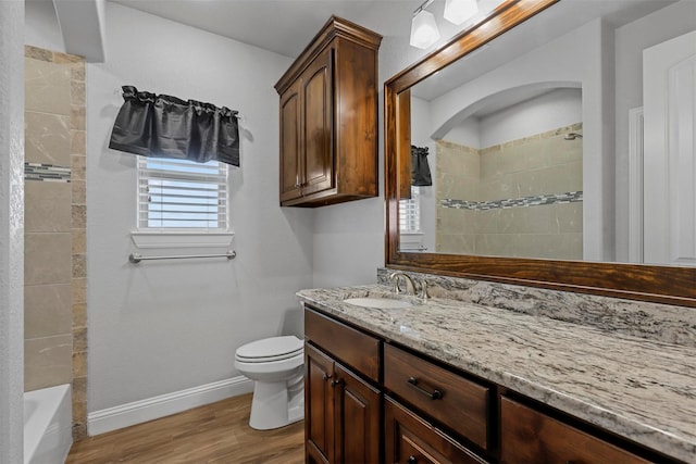 full bathroom featuring vanity, tiled shower / bath combo, wood-type flooring, and toilet