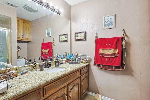 bathroom with a textured ceiling, vanity, and a shower with shower door