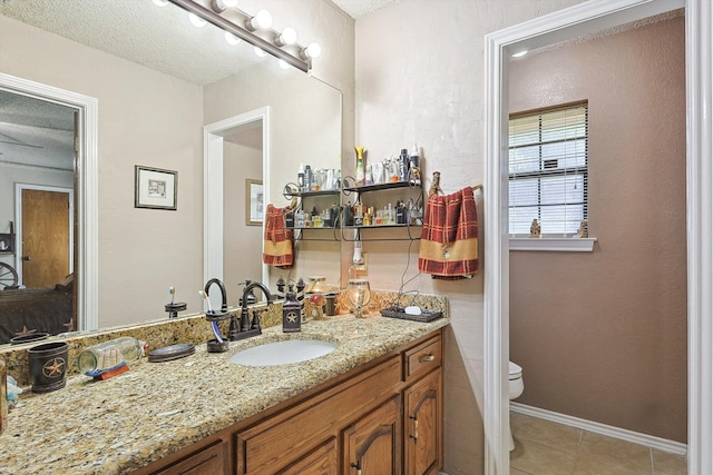 bathroom with vanity, tile patterned flooring, toilet, and a textured ceiling