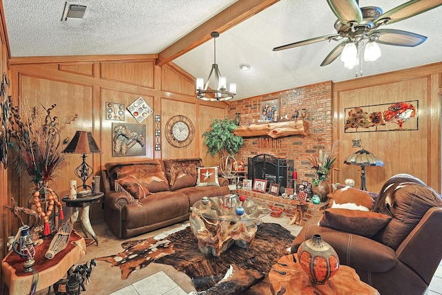 living room featuring wooden walls, ceiling fan with notable chandelier, and a fireplace