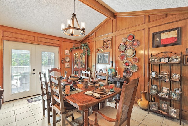 dining space featuring a notable chandelier, a textured ceiling, wood walls, and light tile patterned floors