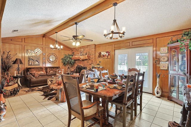 dining room featuring lofted ceiling with beams, ceiling fan with notable chandelier, light tile patterned floors, a textured ceiling, and wooden walls