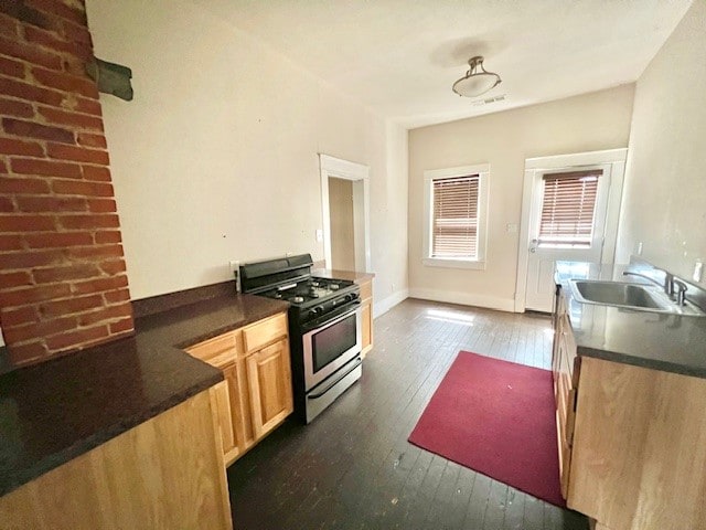 kitchen featuring light brown cabinetry, sink, dark wood-type flooring, and gas stove