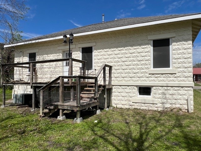 rear view of house with a lawn, a wooden deck, and central AC unit