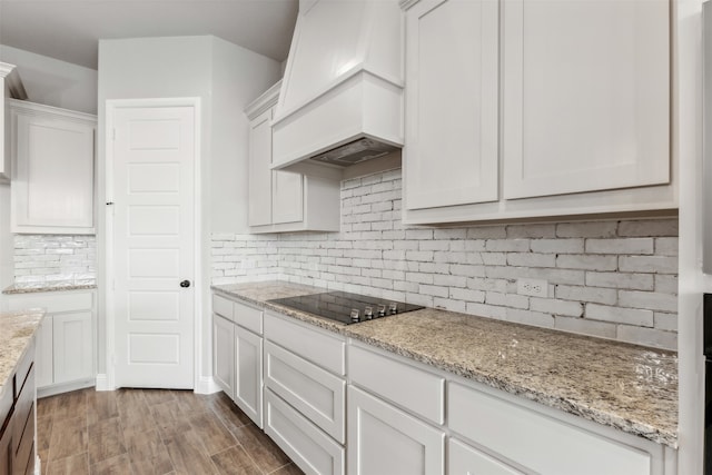 kitchen with hardwood / wood-style flooring, white cabinetry, custom exhaust hood, decorative backsplash, and black electric cooktop