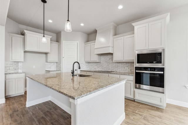 kitchen with a center island with sink, white cabinetry, sink, and stainless steel appliances