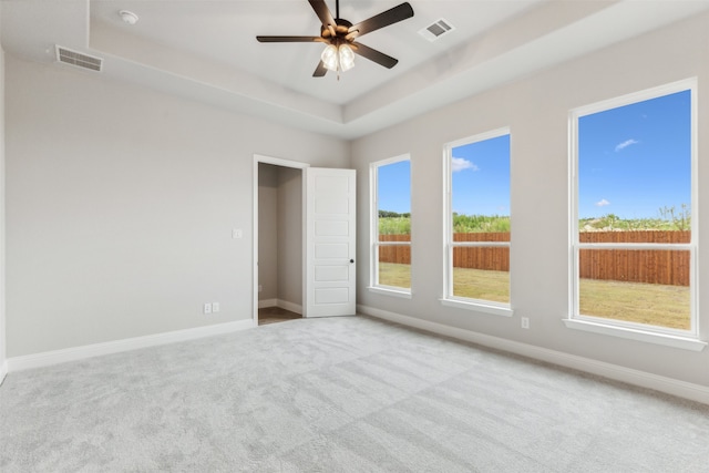 spare room featuring ceiling fan, light colored carpet, and a wealth of natural light