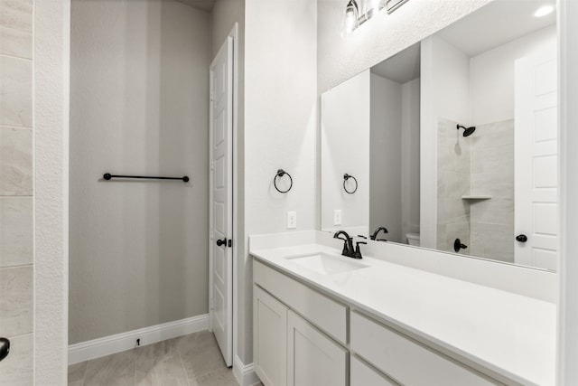 bathroom with a tile shower and vanity