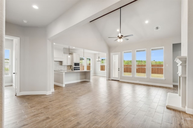 unfurnished living room featuring high vaulted ceiling, light wood-type flooring, and ceiling fan