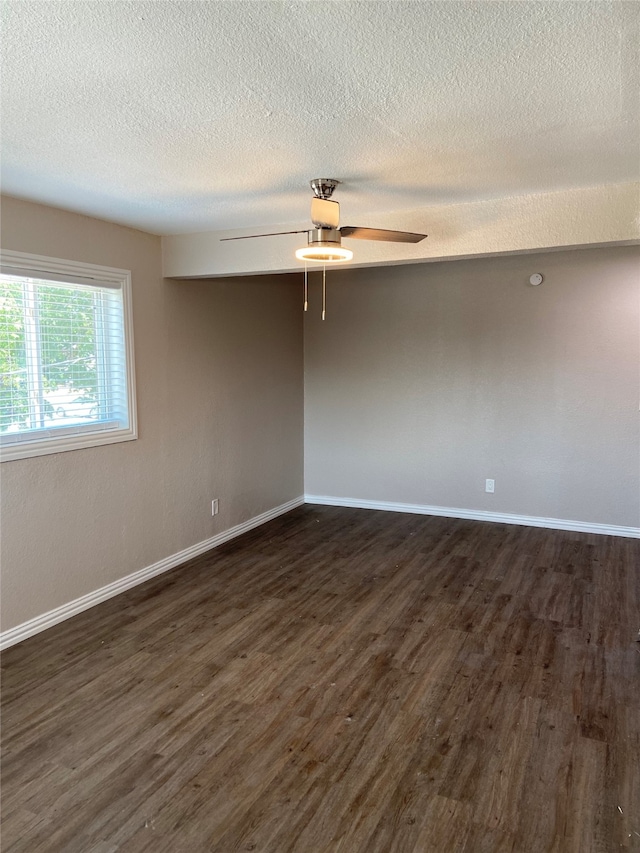 empty room with a textured ceiling, ceiling fan, and dark hardwood / wood-style flooring