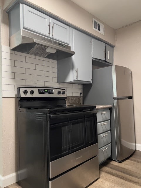 kitchen with gray cabinetry, appliances with stainless steel finishes, light hardwood / wood-style floors, and decorative backsplash