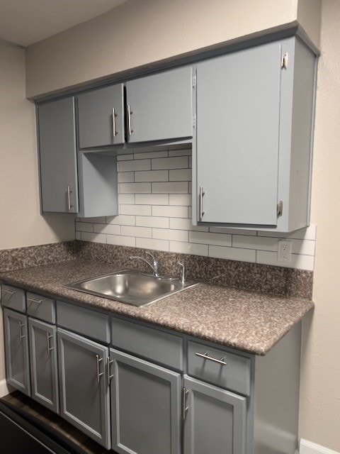 kitchen featuring backsplash, sink, and gray cabinetry