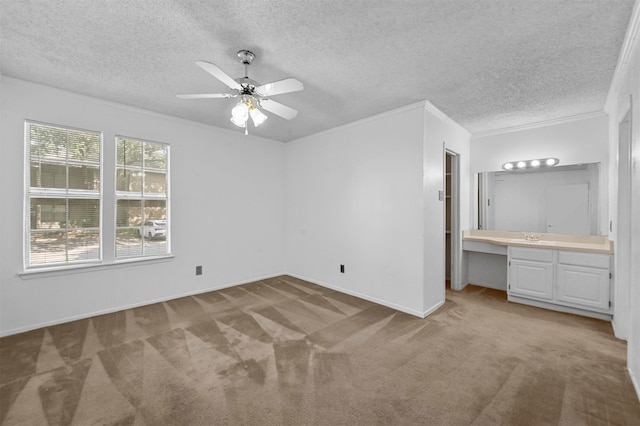 unfurnished bedroom featuring ceiling fan, a textured ceiling, light carpet, crown molding, and ensuite bathroom