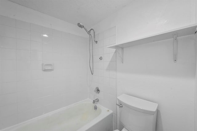 bathroom with a textured ceiling, tiled shower / bath combo, and toilet