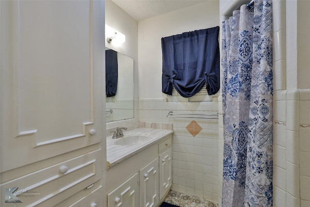 bathroom with a textured ceiling, tile walls, vanity, and curtained shower