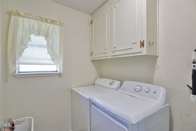 laundry room with cabinets, a textured ceiling, and washing machine and clothes dryer