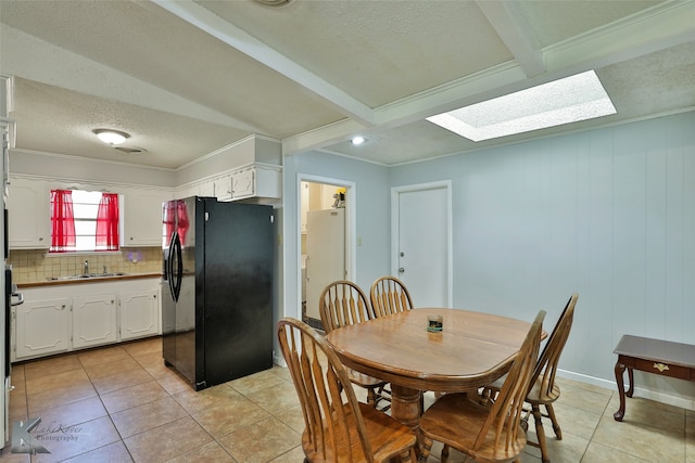 dining room featuring a skylight, wood walls, sink, light tile patterned floors, and crown molding