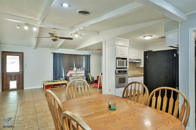 tiled dining space with a textured ceiling, vaulted ceiling with beams, and ceiling fan