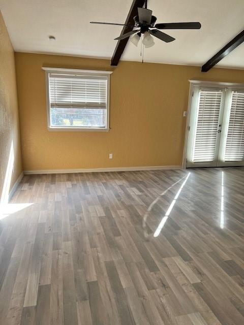 spare room featuring french doors, ceiling fan, wood-type flooring, and beam ceiling