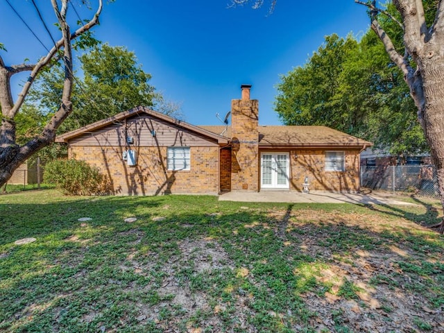 rear view of property with a patio, a lawn, and french doors