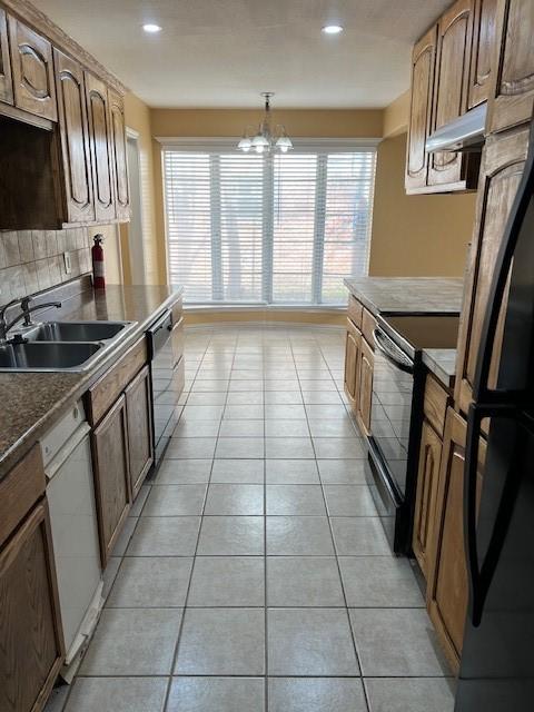 kitchen featuring light tile patterned flooring, sink, backsplash, hanging light fixtures, and black appliances