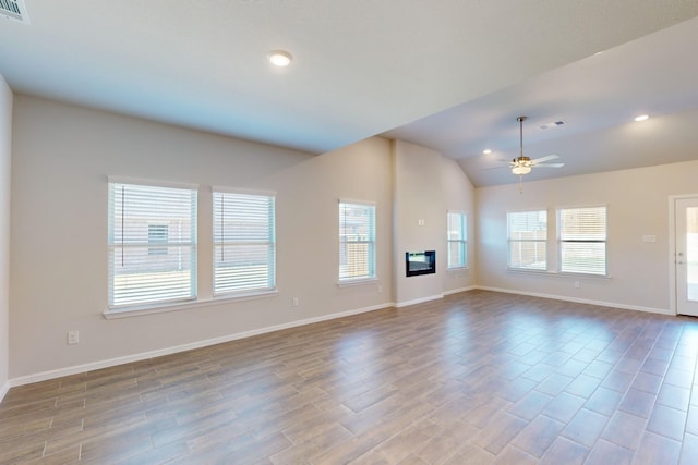 unfurnished living room featuring ceiling fan, vaulted ceiling, and a healthy amount of sunlight