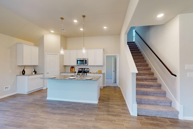 kitchen featuring white cabinets, tasteful backsplash, hanging light fixtures, and appliances with stainless steel finishes