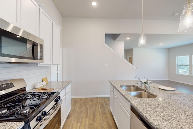 kitchen with sink, stainless steel appliances, white cabinets, and light stone counters