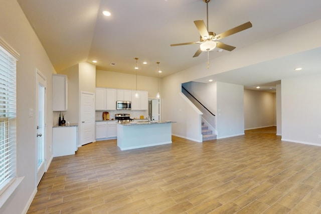 kitchen with pendant lighting, stainless steel appliances, a kitchen island with sink, white cabinets, and ceiling fan