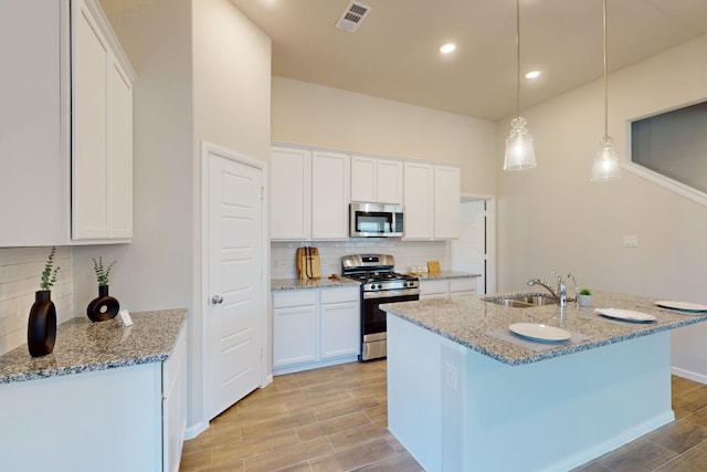 kitchen with stainless steel appliances, white cabinets, sink, and pendant lighting