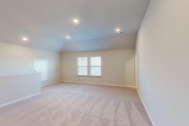 empty room with light colored carpet and lofted ceiling