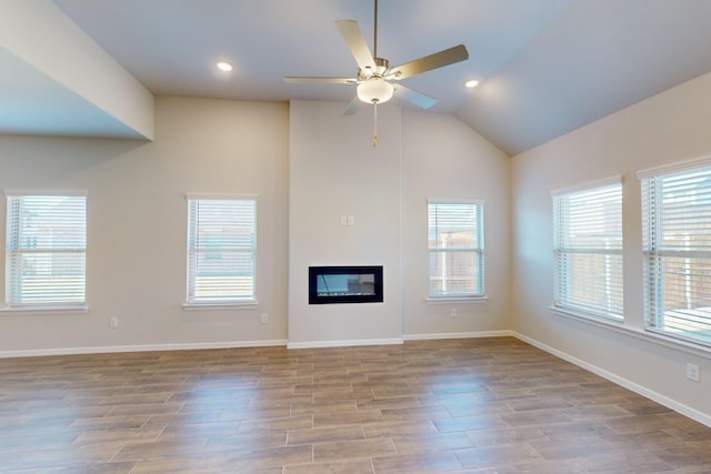 unfurnished living room with ceiling fan, vaulted ceiling, and plenty of natural light